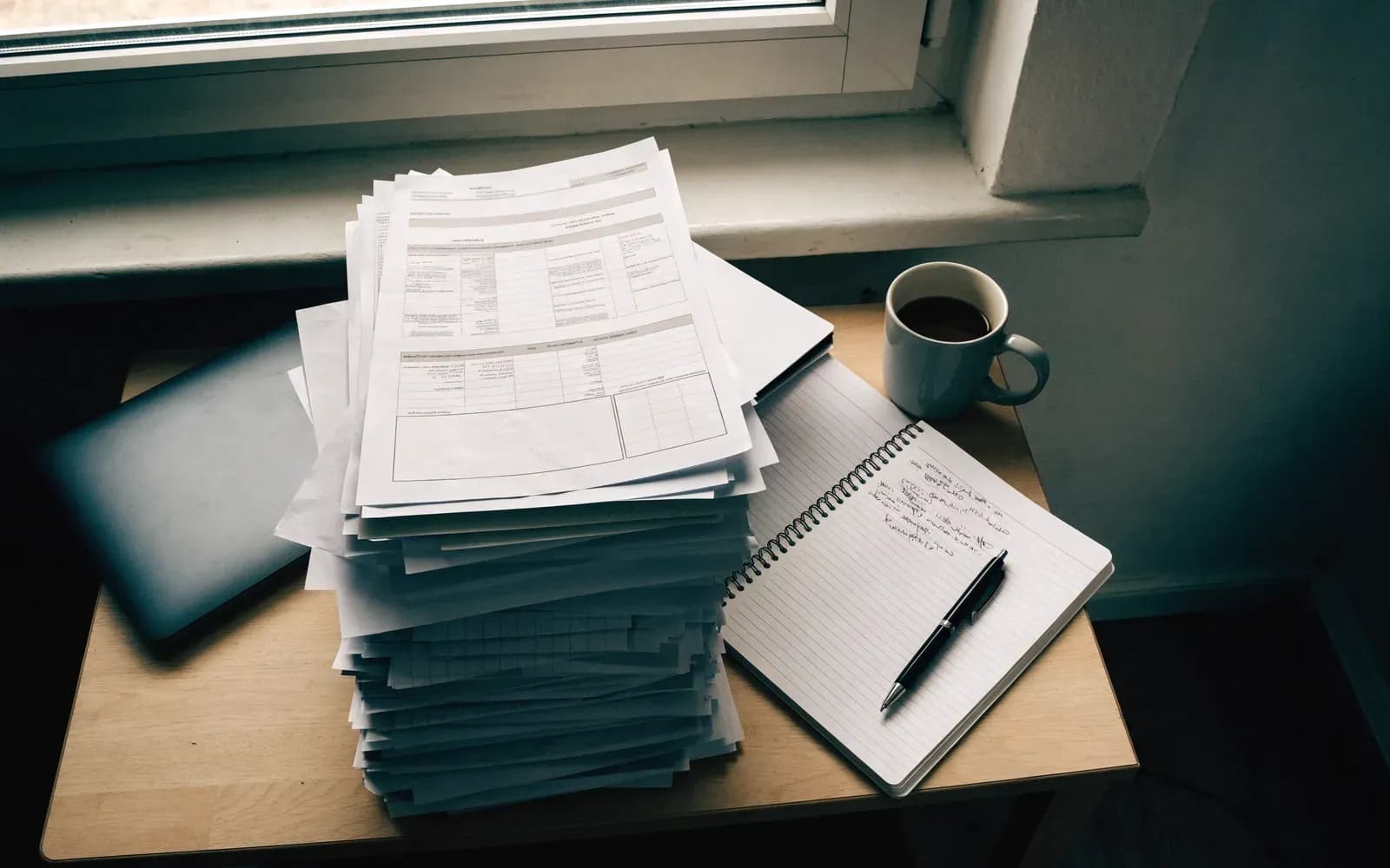 Stapel formulieren en een notitieblok op een bureau bij het raam